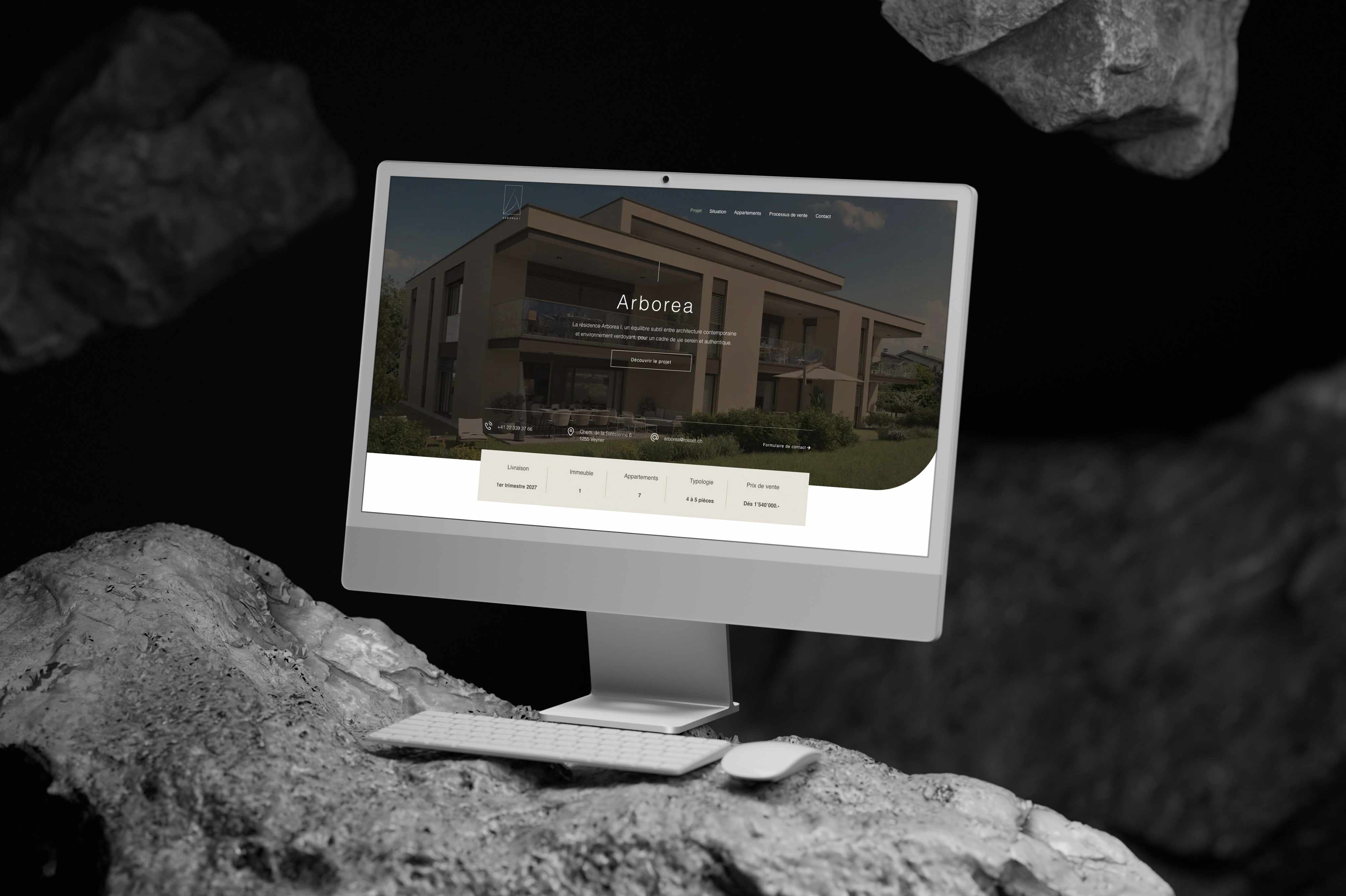 Le site de commercialisation des Résidences Arborea affiché sur un iMac posé au milieu de blocs de pierre
